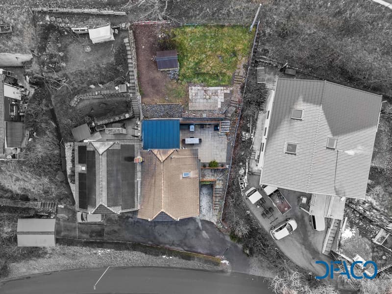 House with solar panels, small garden, garage, and several cars parked
