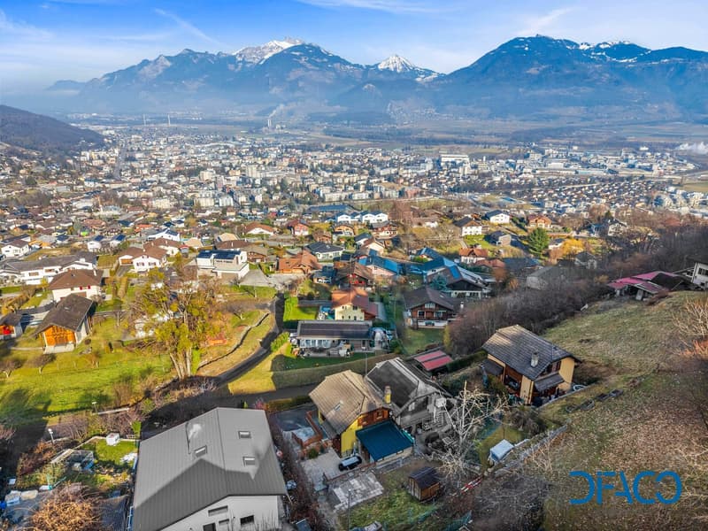 village with multiple houses, surrounded by greenery and mountains