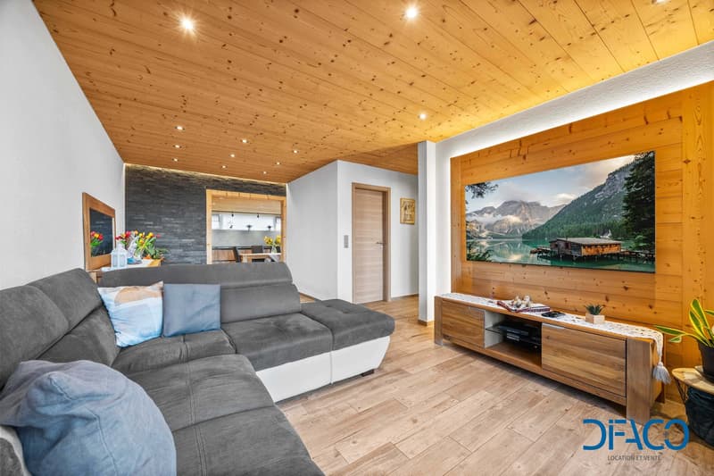 L-shaped sofa, gray cushions, large picture frame, wooden floor, entertainment center, mounted TV