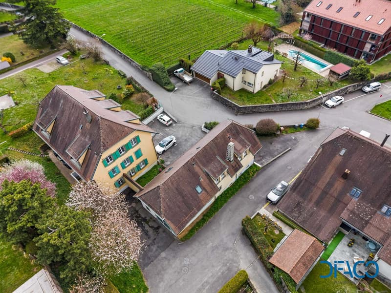 Aerial view of a residential area with several houses, a swimming pool, and a parking lot.