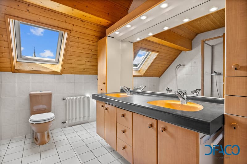 wooden ceiling, white tiles, double sink, toilet, radiator, skylights