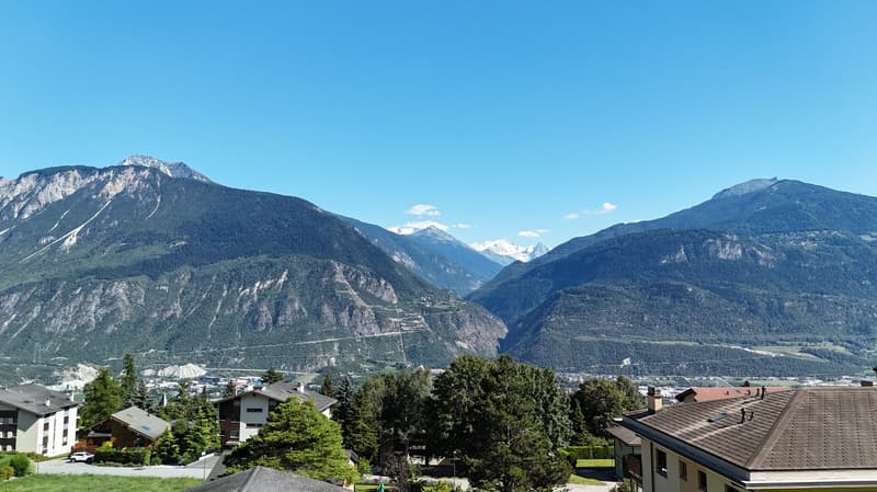 Buildings, mountains, green valley, snow on mountains, blue sky, trees, road