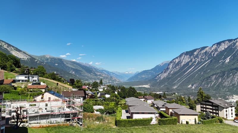 several houses and apartments, mountainous terrain, trees, open green area