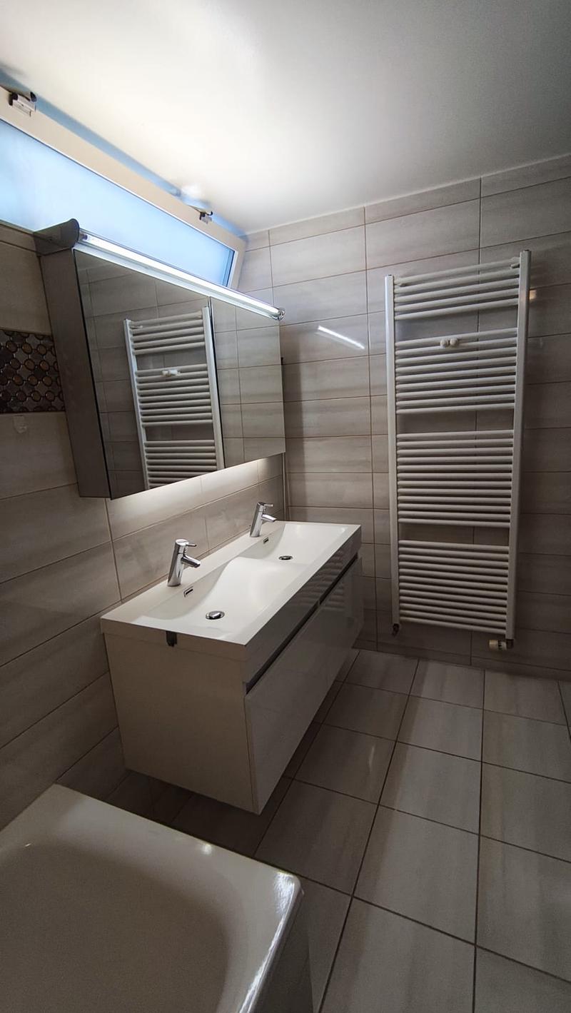Bathroom with bathtub, double sink, mirror, and towel rack