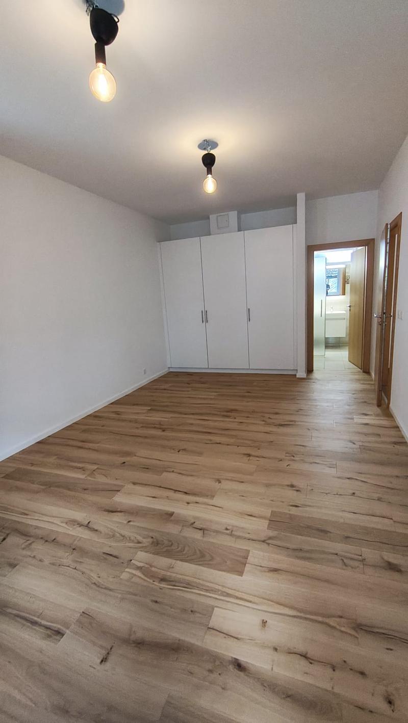 empty room, wooden floor, white walls, two ceiling lights, two white wardrobes, open door