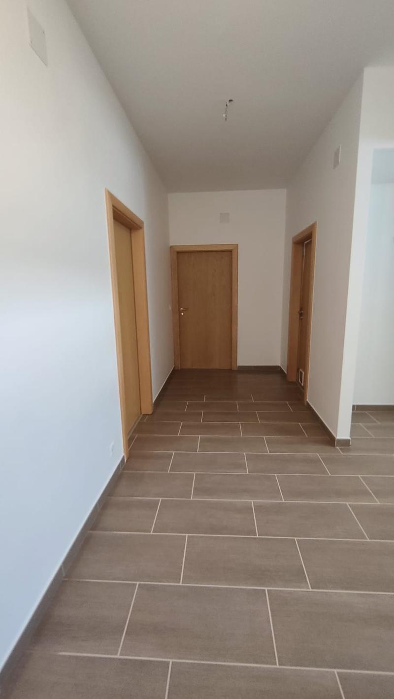 Empty hallway with three doors, tiled floor, white walls