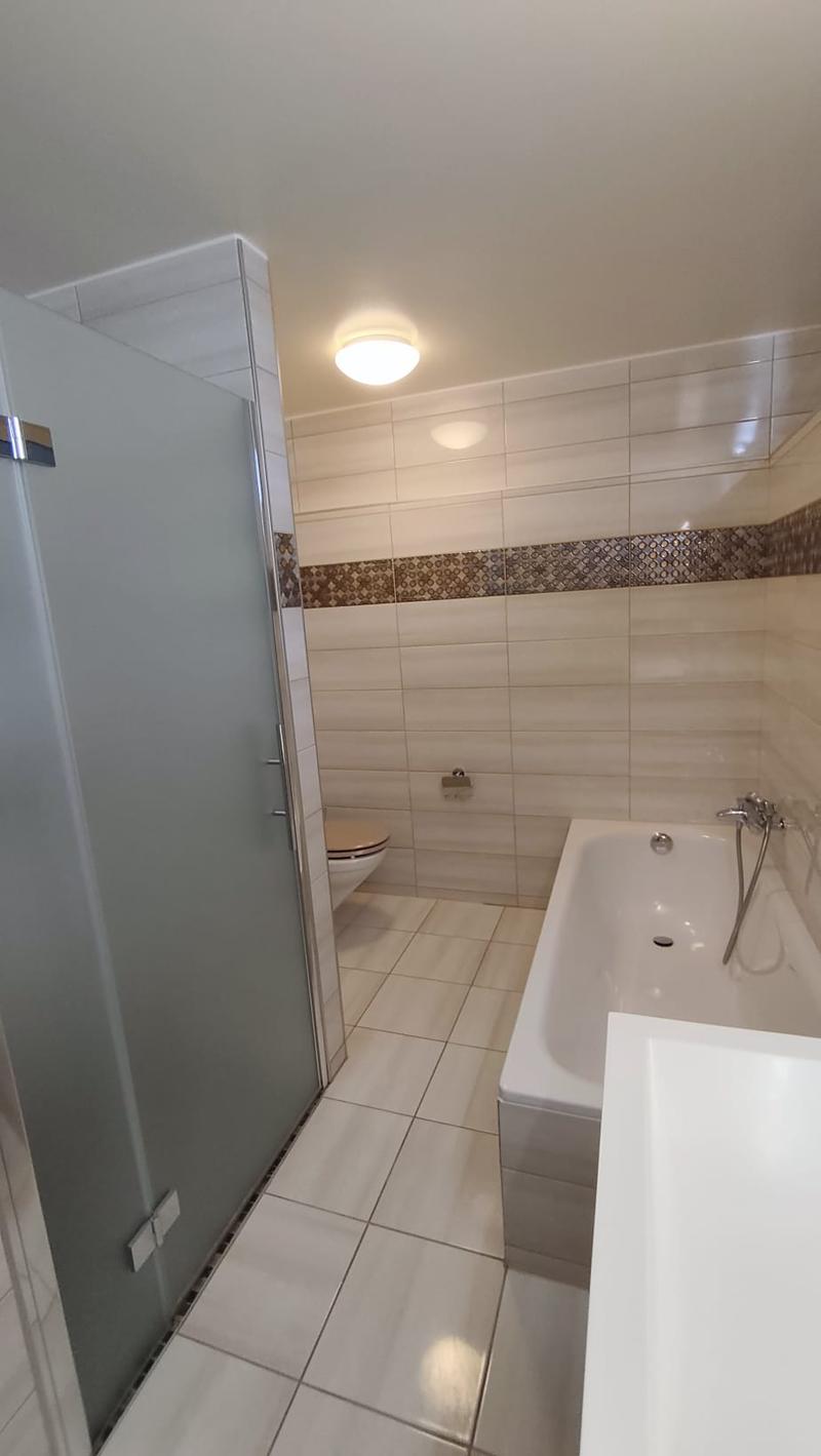Bathroom with white tiles, bathtub, shower, toilet, and a sink.