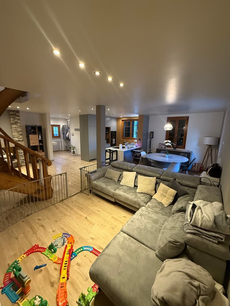 open space living room with couch, dining table and chairs, wooden staircase