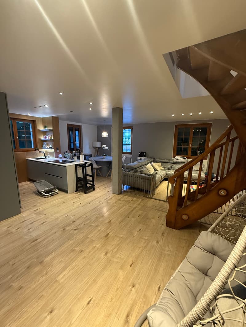 large open plan living area, hardwood floor, spiral staircase, modern kitchen, sectional sofa, dining table and chairs, lamps, side table, window