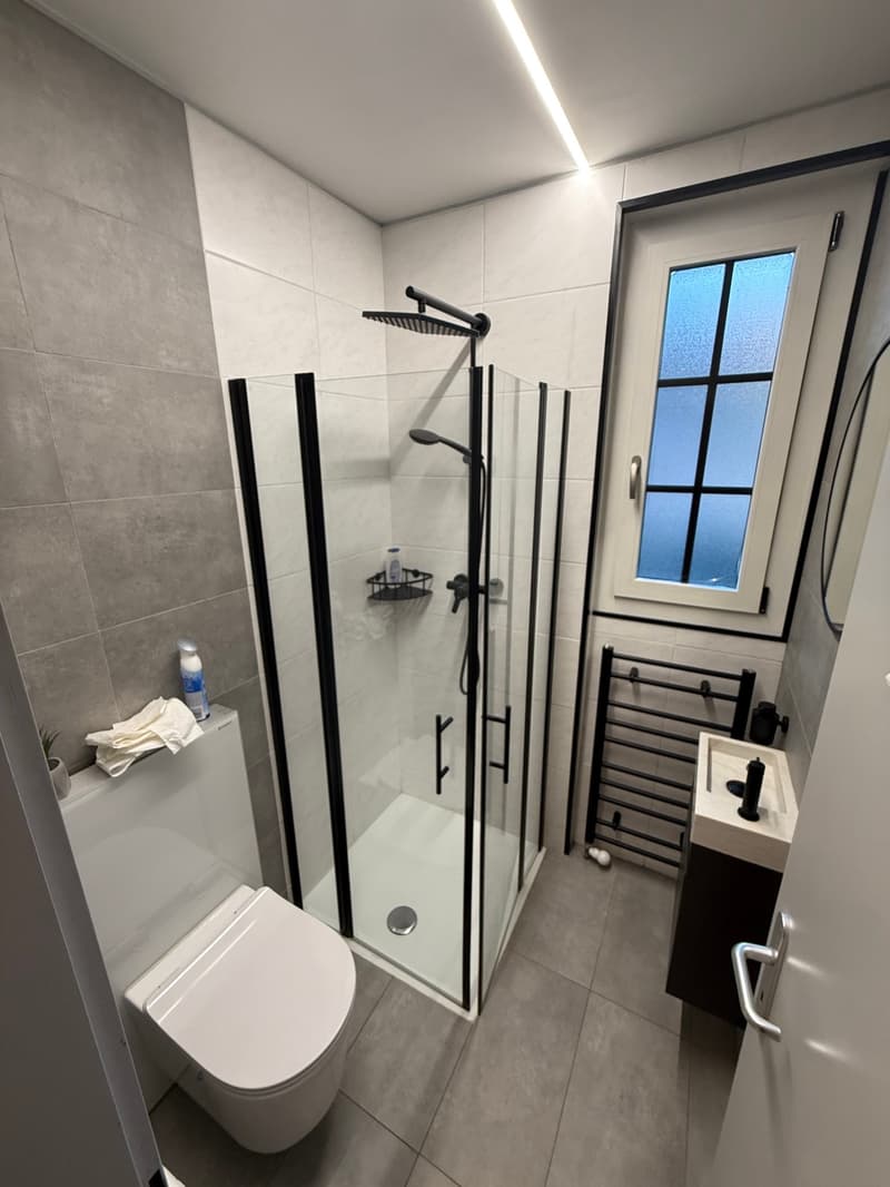 modern bathroom with glass walk-in shower, white toilet, tiled floor, sink, and towel rack