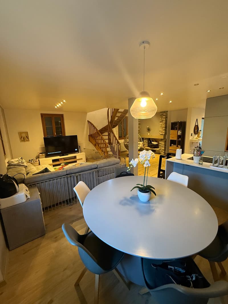 dining area with round table and chairs, living room with couch, tv, and fireplace