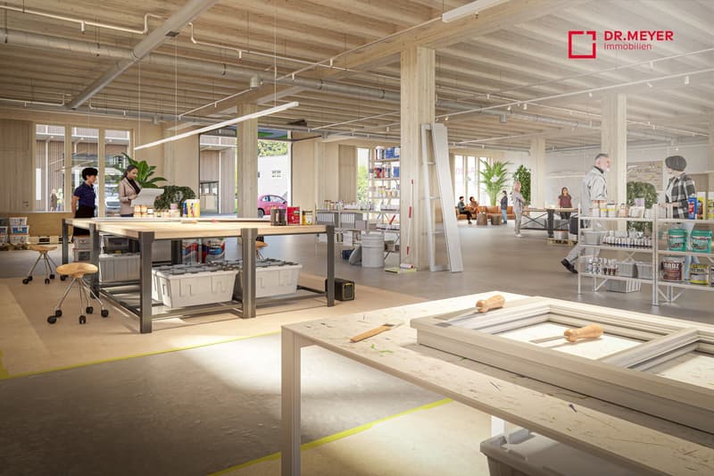 large room, several desks, tables, large windows, plants, shelves, people