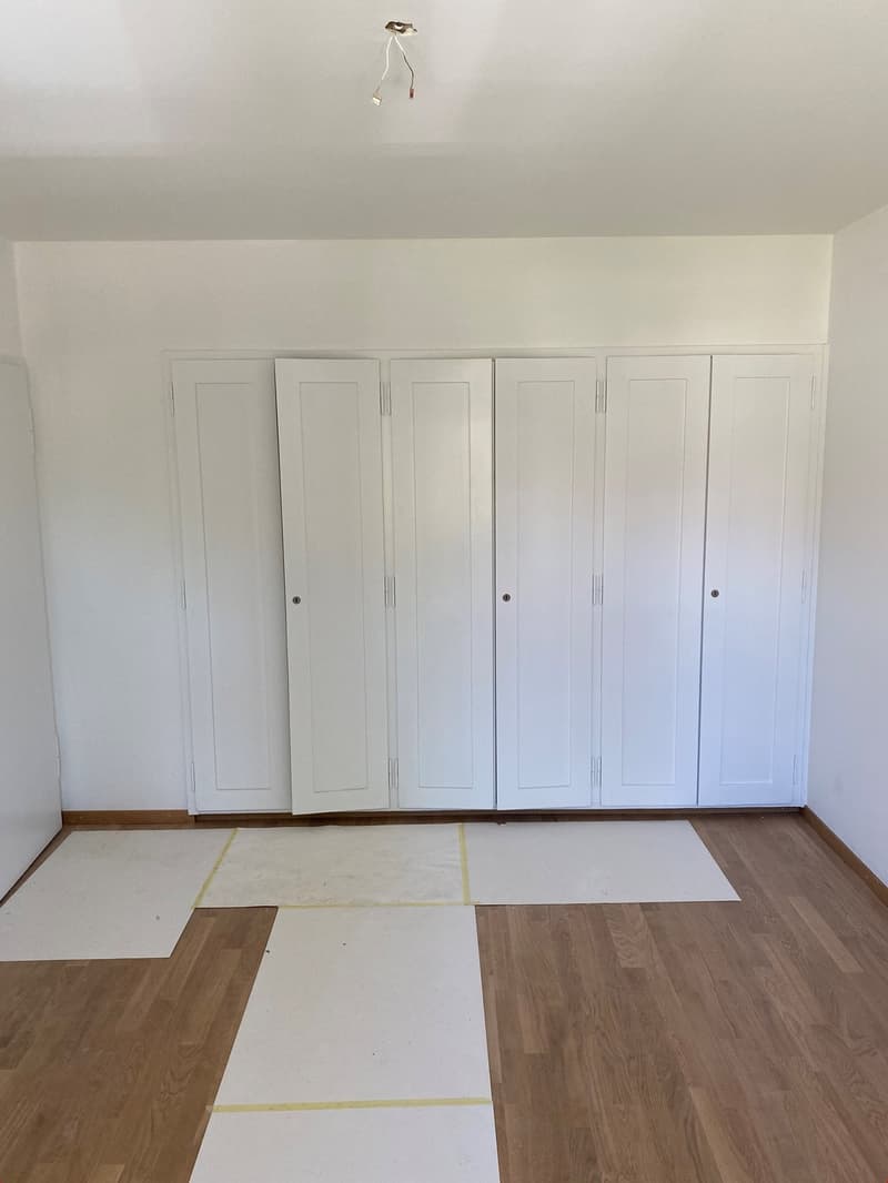 empty room, wooden floor, white walls, white closets, white floor coverings