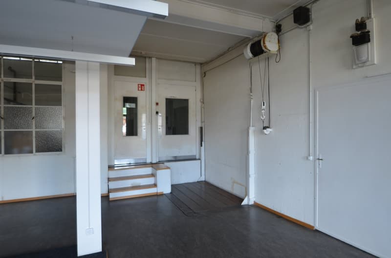 Empty room, white walls, wooden stairs, wooden floor, industrial light fixtures, large glass windows