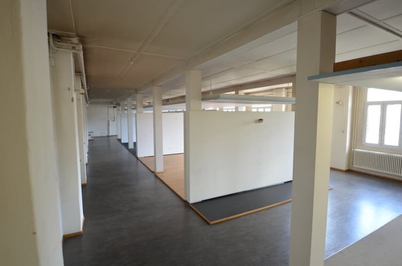 empty large room, long hallway, white walls, gray flooring, radiator, large windows