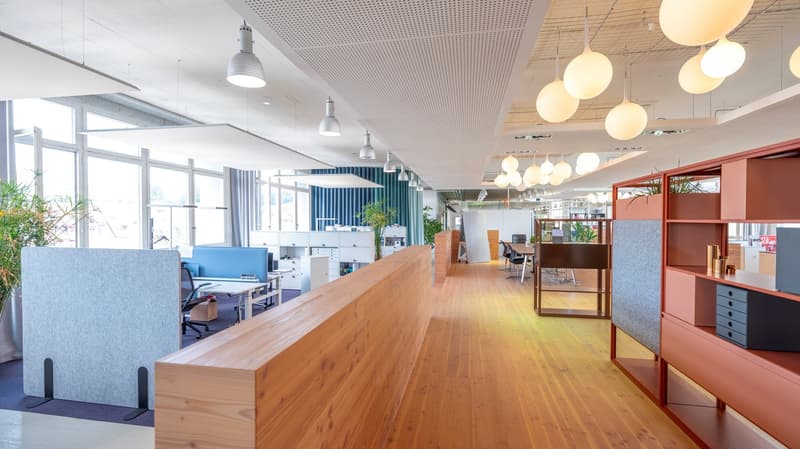 Modern open space office with wooden floor, suspended lamps, modular office furniture, glass windows