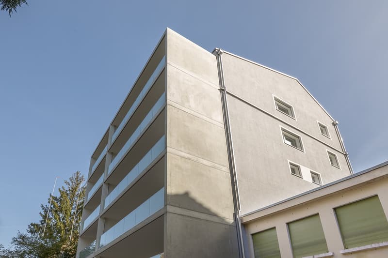 modern multistory building, grey exterior, large glass windows, white shutters