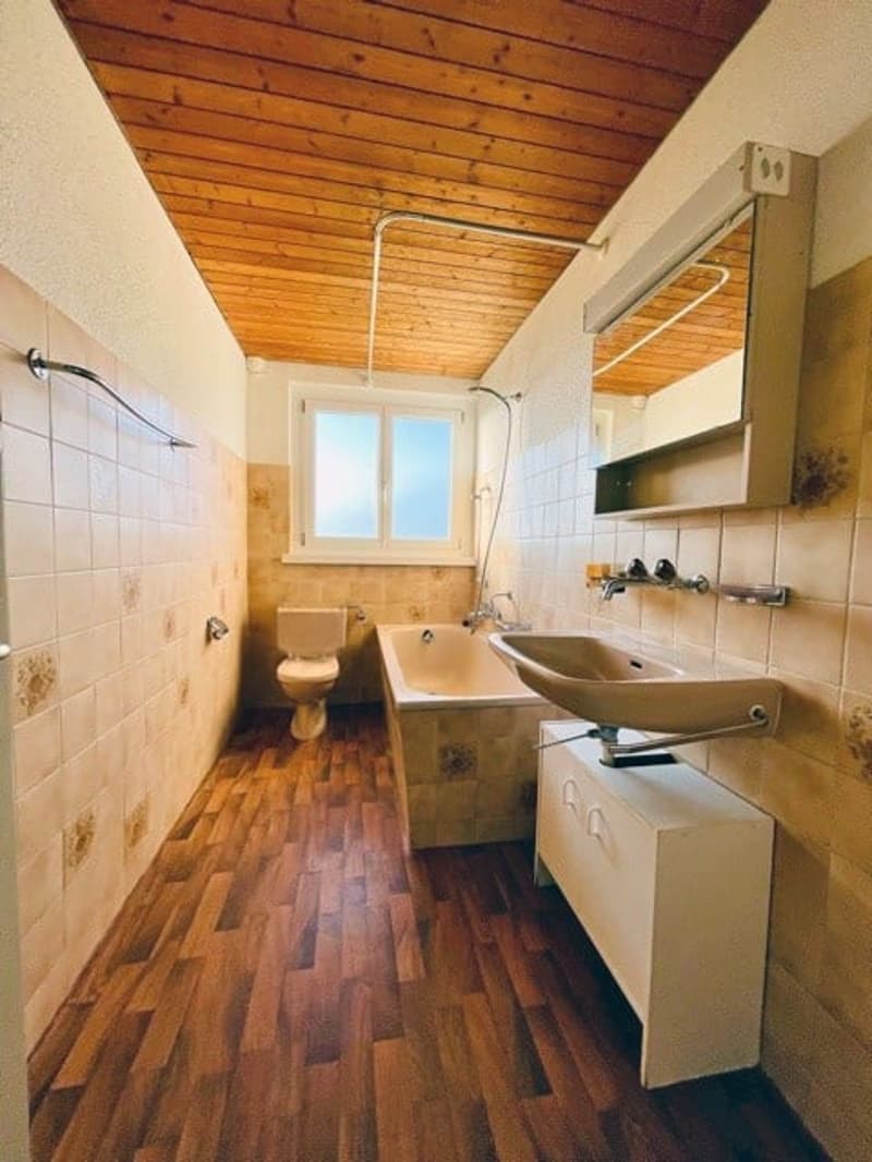 Bathroom with wooden floor, bathtub, sink, toilet, mirror, wooden ceiling