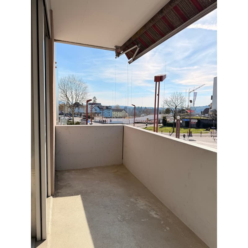 Empty balcony with concrete floor, white walls, and a view of the city