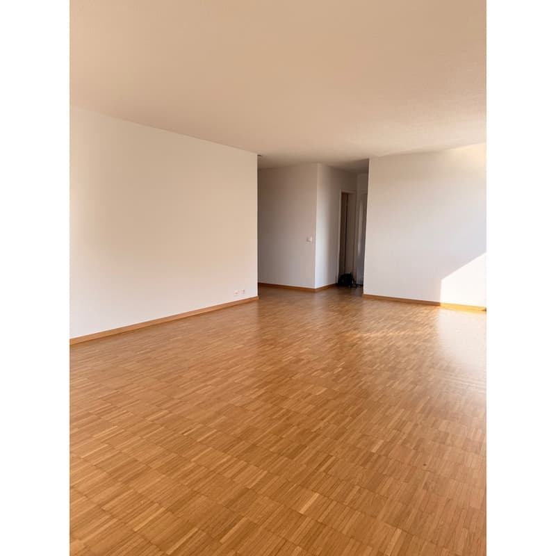 Empty room with wooden floors, white walls, and two power outlets on the left wall.
