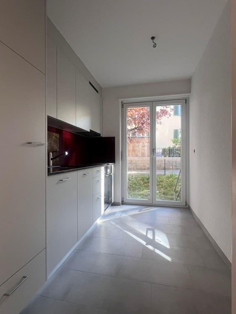 modern kitchen with white cabinets, gray tiled floor, sliding glass door, stainless steel faucet
