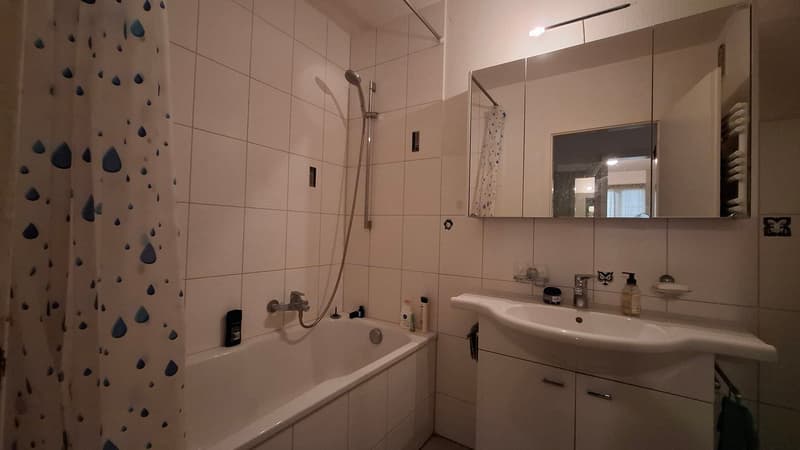 Bathroom with bathtub, shower, sink, mirror, and cabinets