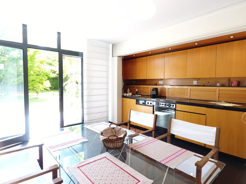 modern kitchen with wooden cabinets, stainless steel oven, gas stove, glass doors and table, and chairs