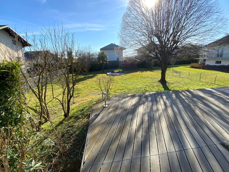 backyard with wooden deck and grassy lawn, trees, and plants