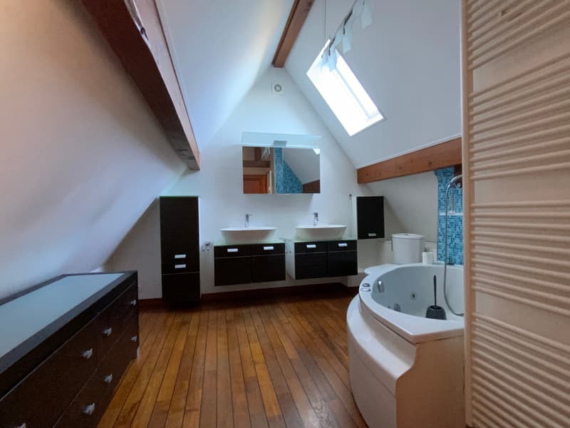 wooden floors, two sinks with cabinets, a toilet, a bathtub, a skylight