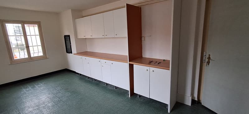 empty room with green floor, several cabinets, window