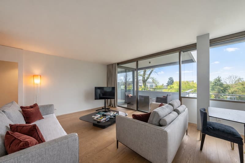 modern living room, grey sofa, black center table, TV, large windows with balcony