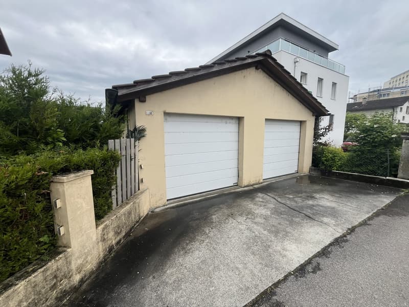 A garage attached to a building with white garage doors.