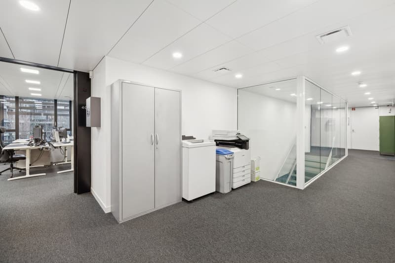 white walls, carpet floor, glass wall, glass door, glass window, office desks, office chairs, printers, trash bins