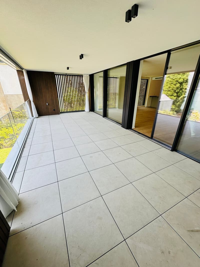 large balcony, white tiled floor, large glass windows, wooden railings, outdoor view