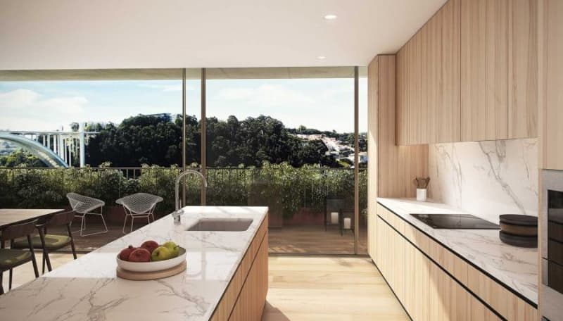 Spacious kitchen with large windows offering a scenic view, marble countertops, wooden cabinets, and a balcony or terrace area with outdoor seating
