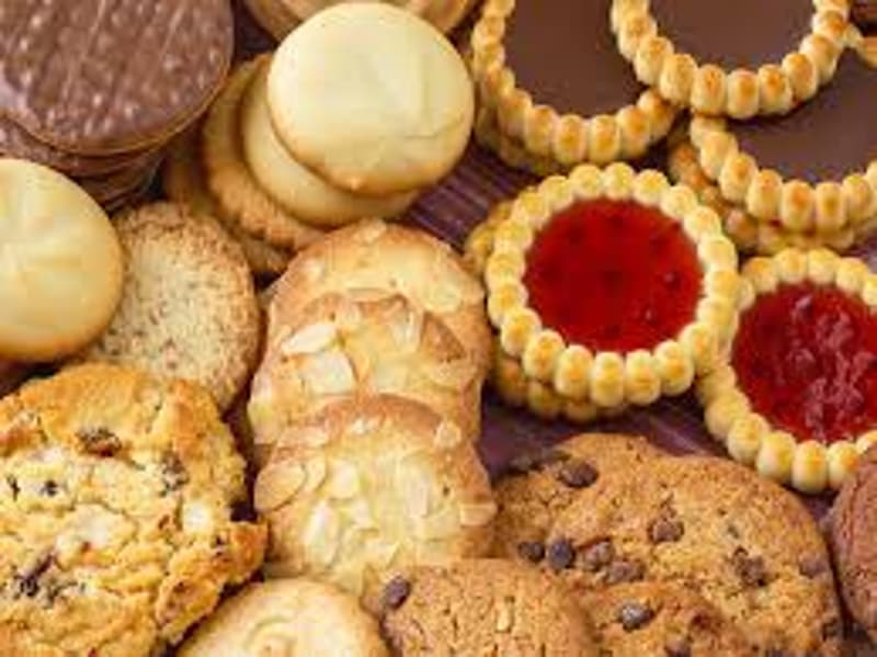 The image shows a variety of baked goods, including cookies, pastries, and other desserts. There are different shapes, textures, and colors, such as round cookies, crumbly biscuits, and jam-filled tarts. The overall impression is of a delicious and tempti