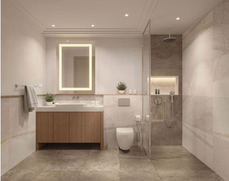 Spacious bathroom with a large vanity, a toilet, and a walk-in shower with a rainfall showerhead. The walls are covered in neutral-colored tiles, and the room features recessed lighting and a lighted mirror.