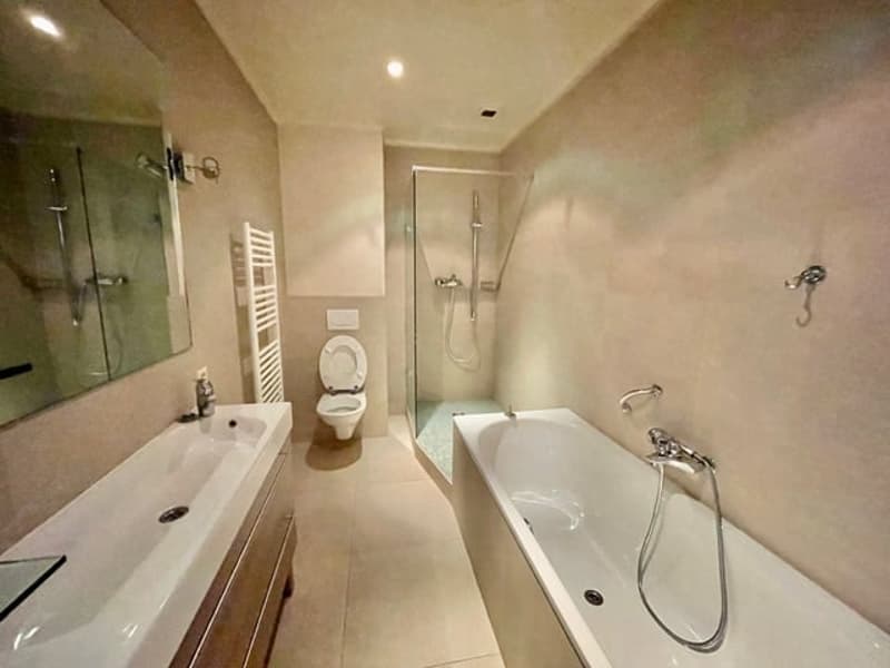 Spacious bathroom with a bathtub, toilet, and shower area. The room has a neutral color scheme and includes a washing machine.