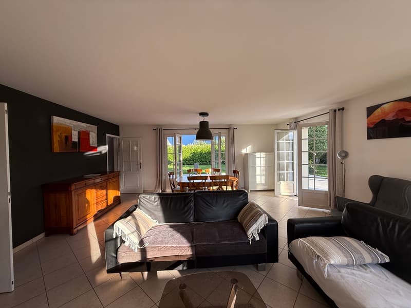 modern decor, black leather sofas, dining table with chairs, glass doors leading to a balcony, wooden cabinet, ceiling lamp, picture frames, tiled floor, lamps