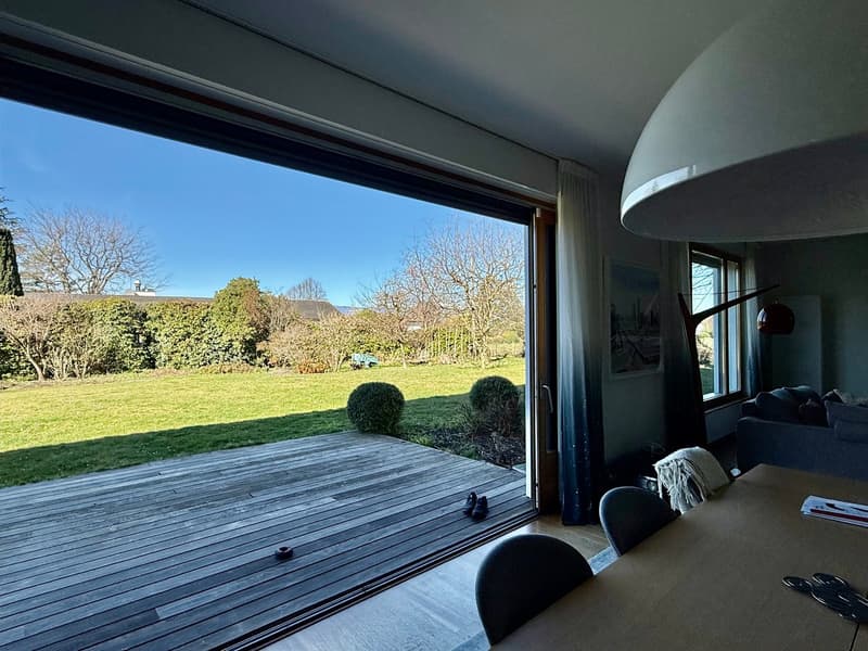 large windows, wooden floor, glass sliding doors leading to terrace, indoor view of a garden