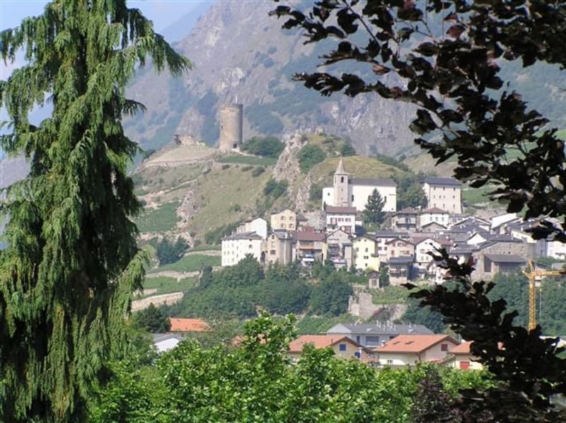 Mountain village, several buildings, hilly landscape, greenery, castle tower