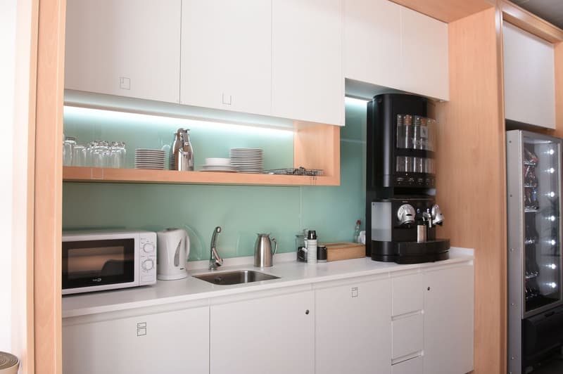 Modern kitchen with white cabinets, open shelving, stainless steel sink, microwave, coffee maker, and dishwasher