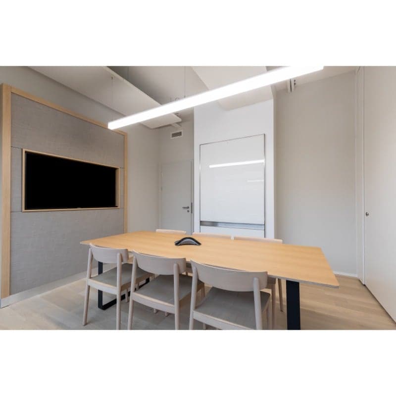 modern meeting room with wooden table, chairs, TV, and white walls