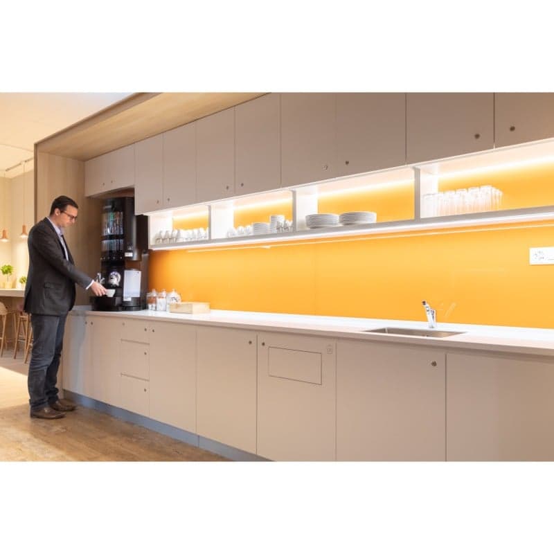 modern kitchen with white cabinets, yellow wall, wooden floor, sink, faucet, coffee machine, shelves with plates and glasses