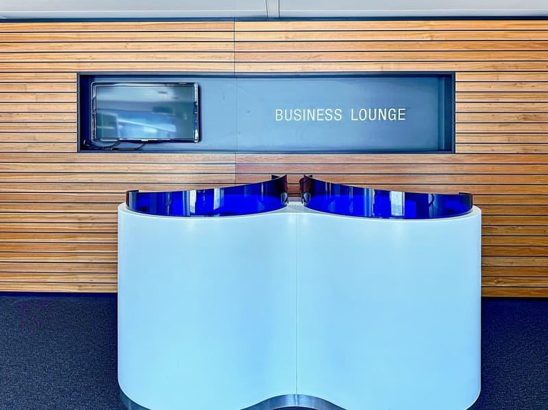 Reception desk with blue top, business lounge sign, wooden paneling, television