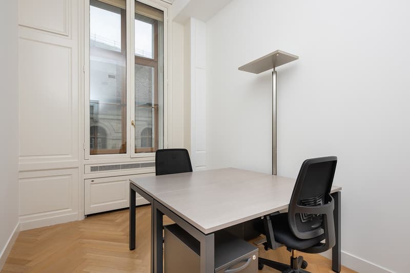 empty room, 2 office chairs, grey table, white walls, hardwood floor, window