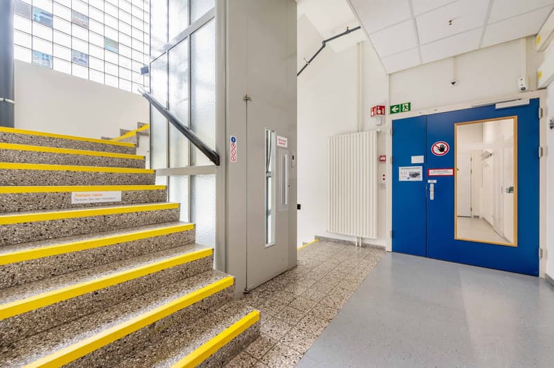 stone stairs, lift, white tiled wall, white tiled floor, blue doors, white radiator