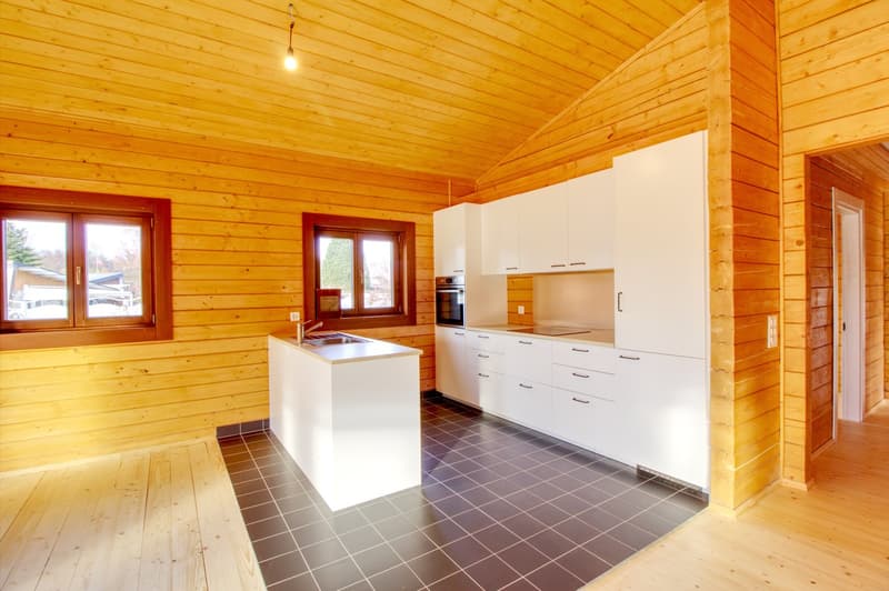 kitchen with wooden walls, white cabinets, black tiled floor, sink, oven, windows