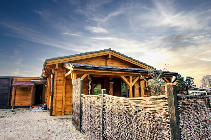wooden house, gray roof, wooden porch, wooden fence, gravel driveway