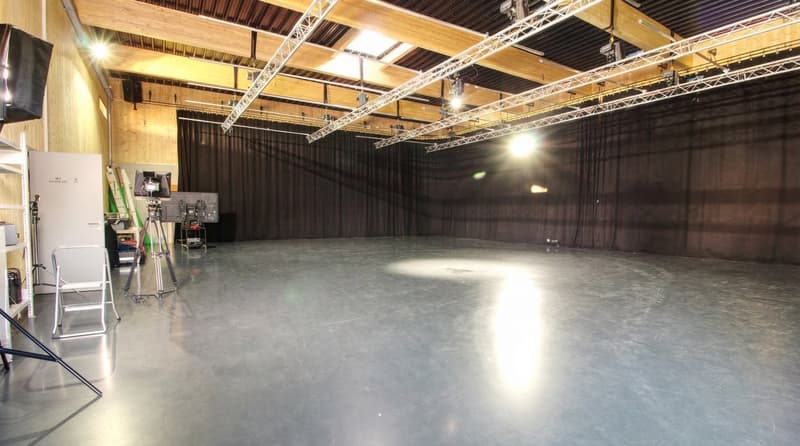 large open space, metal trusses, black curtains, tripods, lights